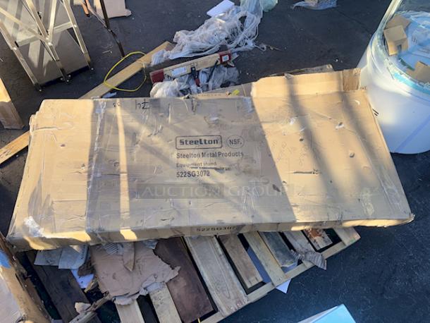 BRAND NEW! "Steelton 30" x 72" 18-Gauge Stainless Steel Equipment Stand with Undershelf and Galvanized Legs. In original packaging, unit has some easily fixable denting/bending (see photos). - Image 1 of 7