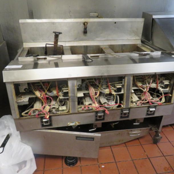 One Henny Penny  Natural Gas 3 Vat Open Fryer On Casters With 6 Baskets. Model# OFG-323.  120 Volt. Missing Front Panels, And 1 Bottom Door. 49.5X33.5X44. $25,367.00 - Image 1 of 1