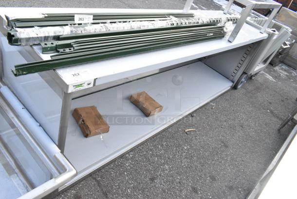 BRAND NEW SCRATCH AND DENT! Regency 600EBT2496 24" x 96" 16 Gauge Type 304 Stainless Steel Enclosed Base Table with Open Front and Adjustable Midshelf - Image 1 of 2