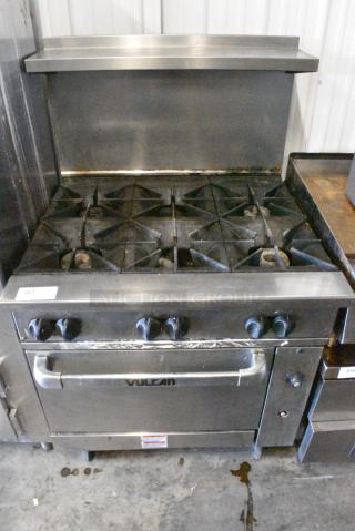 Vulcan 36S-Y1A Stainless Steel Commercial Natural Gas Powered 6 Burner Range w/ Oven, Over Shelf and Back Splash on Commercial Casters.