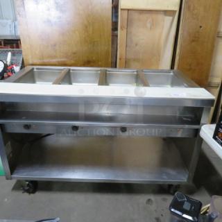 One Delfield 4 Well Electric Steam Table With A Cutting Board, And  SS Under Shelf On Casters. WORKING WHEN REMOVED,.  Model# EHE160C. 208-230 Volt. 1 Phase. Hardwired.  60X31.5X37. $5409.00