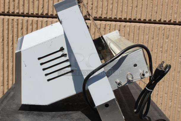 Industrial meat slicer with adjustable blade, metal construction, wear marks, and attached power cord. Good condition.