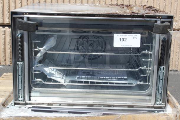 Industrial oven with glass front, two metal racks, and visible internal fan. Auction tag reads "102 QTY, PCIAuctions.com." Condition shows wear.