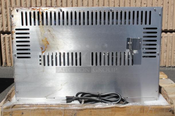 Metal appliance back panel with ventilation slots, showing signs of rust and scratches; bundled power cord included.