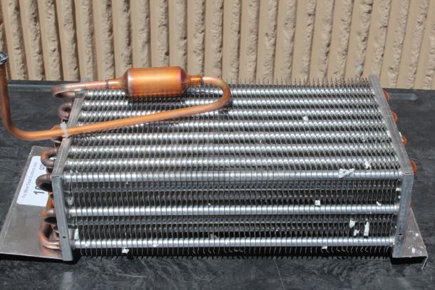 Metal finned heat exchanger with copper tubing, appearing in used condition. No discernible labels or markings.