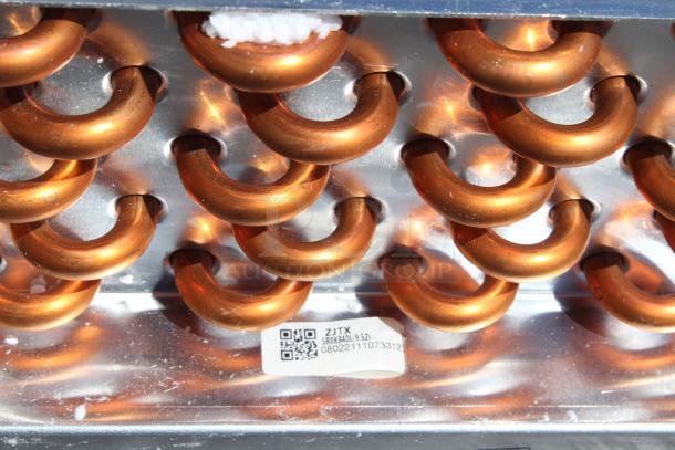 Copper heat exchanger coil with a shiny metal casing, featuring a label showing QR code and numbers "5RX340L(9.52) 08022111073312".