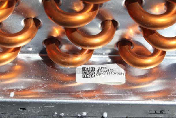 Copper coils in a metal assembly with label indicating model ZJTX, 5R3K340L(9.52), and serial number 08022111073312.