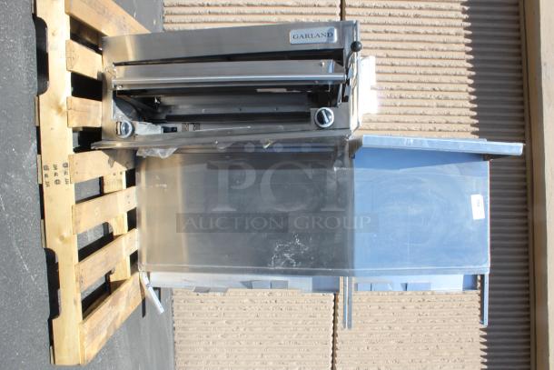 Garland stainless steel commercial range on pallet, used, includes knobs and visible brand label, ideal for restaurant use.