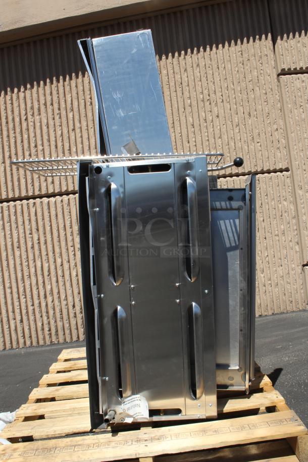 Stainless steel outdoor grill on a wooden pallet, new condition. Features side shelves, visible gas connection marked "Natural."