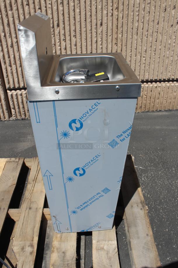 Stainless steel utility sink, new, protective film with "Novacel" branding, hose and parts inside basin.