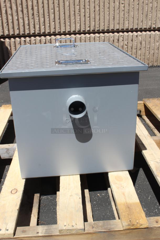 Gray metal grease trap with diamond plate lid, outlet marked, new condition, on wooden pallet.