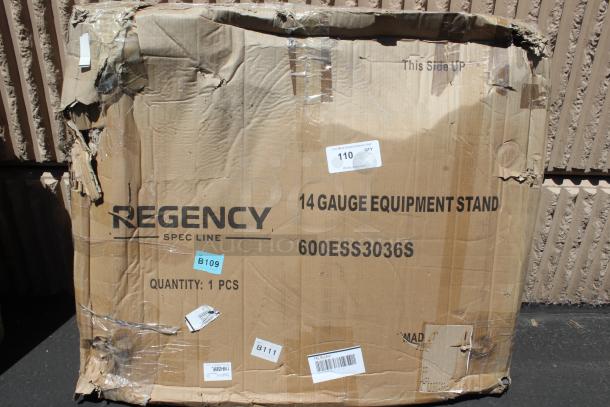 Damaged cardboard box containing Regency Spec Line 14-gauge equipment stand, model 600ESS3036S, with visible shipping labels.