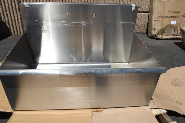 Stainless steel wall-mounted utility sink, new. Features a backsplash and mounting holes. Slight packaging marks visible.