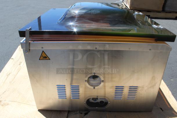 Industrial vacuum packaging machine, stainless steel body, reflective top, caution sticker. In good condition.