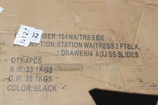 Cardboard box with labels reading: "Station Waitress 2 FT BLK, 1 Drawer/4 Adjustable SS Slides, Color: Black." Scuff marks visible.