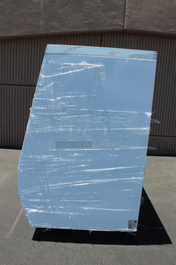 Large appliance wrapped in protective film on pavement; packaging label visible indicating manufacturer and model details.