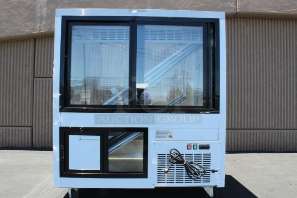 Commercial refrigerated display case with sliding glass doors, white frame, visible control panel and power cord, in good condition.