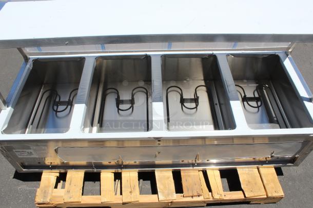 Stainless steel four-well steam table with heating elements, in good condition, mounted on a wooden pallet.