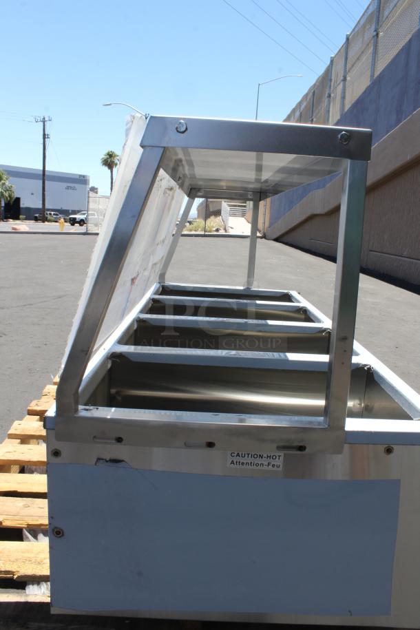 Stainless steel food warmer with glass sneeze guard, visible "CAUTION-HOT" label, in used condition.