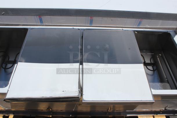 Commercial stainless steel hot food bar with two covered sections, heating elements visible, in fair condition.