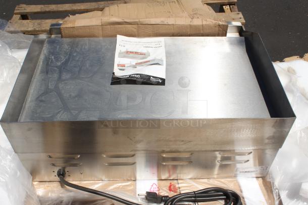Stainless steel countertop griddle, new, with user manual on top. Power cord included. Slight surface marks.