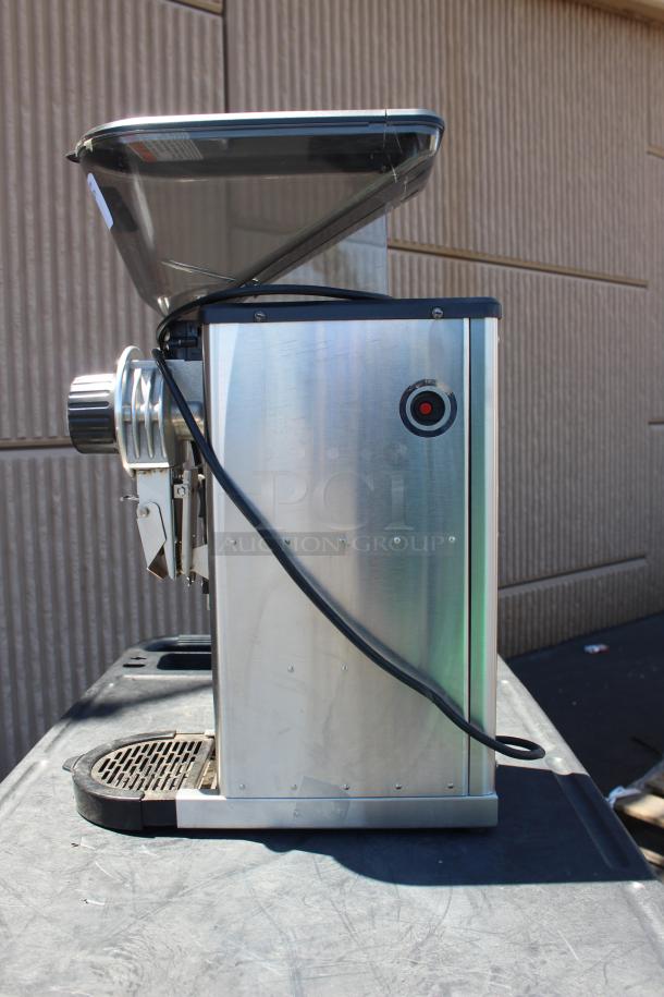 Stainless steel commercial meat grinder with hopper, visible power cord, and mounted on a black surface. Good condition.