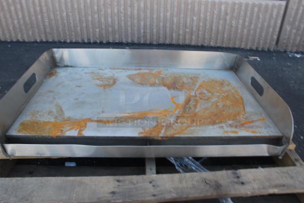 Large stainless steel tray with handles, showing rust and discoloration on the surface, on a wooden pallet. Suitable for restoration.