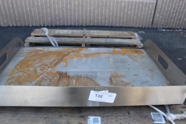 Large stainless steel tray with side handles, marked with auction tag "132 QTY." Surface shows signs of rust.