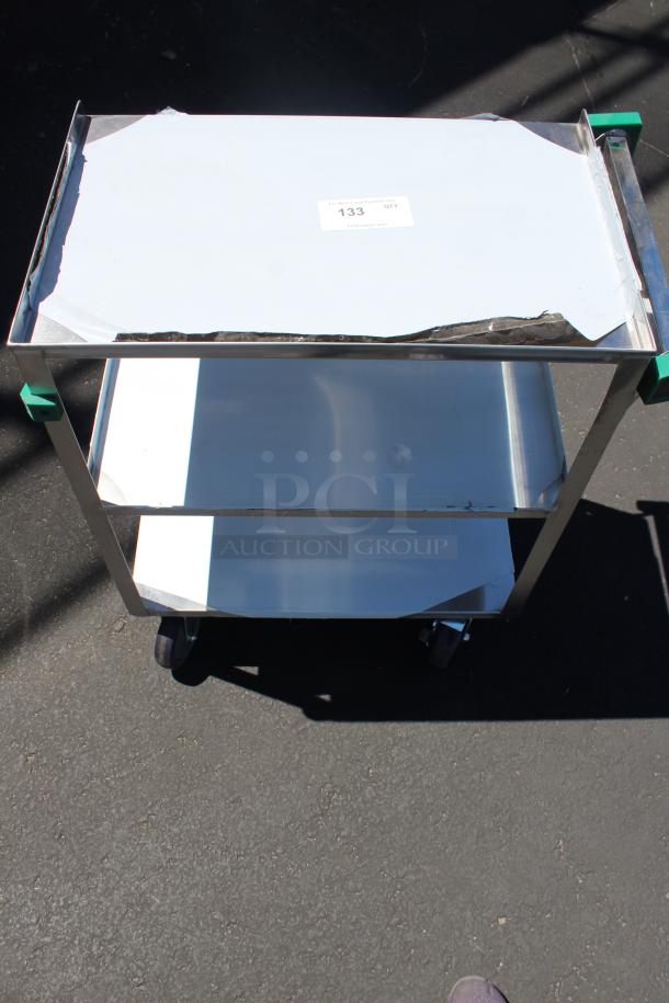 Stainless steel utility cart with three shelves, scuffed top, and visible tag indicating quantity "133". Durable and mobile on wheels.