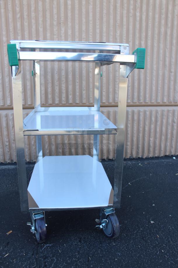 Chrome utility cart with two shelves, rubber wheels, and green handle grips. Appears in excellent condition.