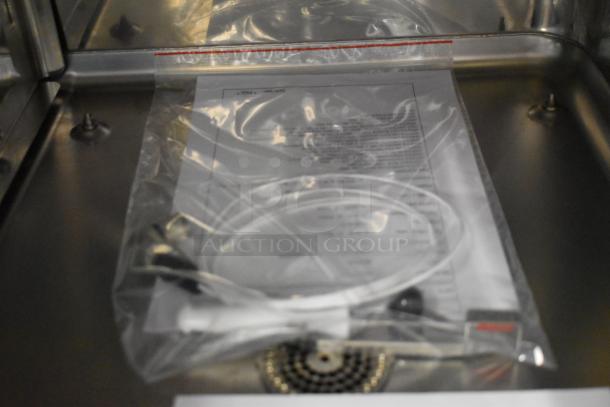 Stainless steel interior of a Bakers Pride AEHE061R combi convection oven with sealed manuals and accessories.