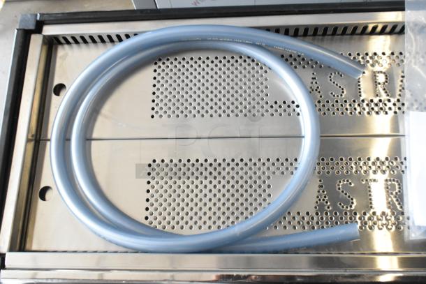 Stainless steel surface of Astra Mega III M3S-018 espresso machine, new with minor scratches. Visible embossed "ASTRA" branding.