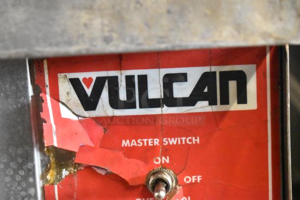 "Vulcan logo with master switch, worn label, indicating oven function controls."