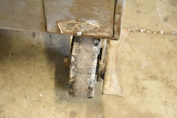 Worn caster on Vulcan VC4CD stainless steel commercial convection oven; partial warning label visible.