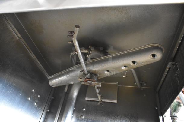 Stainless steel commercial corner pass-through dishwasher interior, highlighting spray arms and piping. Appears in used condition.