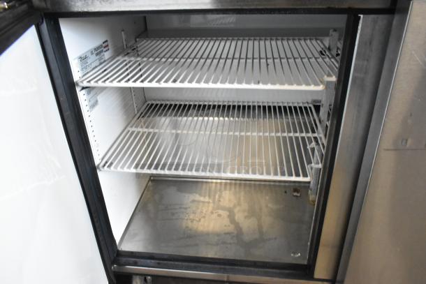 True TSSU-48-12 commercial sandwich prep table, stainless steel, interior shelving, model label visible, on casters.