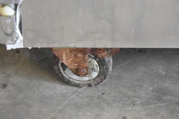 Rusted caster of Leader ESSM48 stainless steel prep table, visible wear on wheel; commercial use, 115 volts, 1 phase.