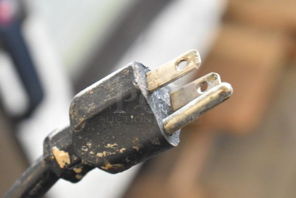 Close-up of a two-prong electrical plug with visible wear, associated with the Leader ESSM48 prep table.