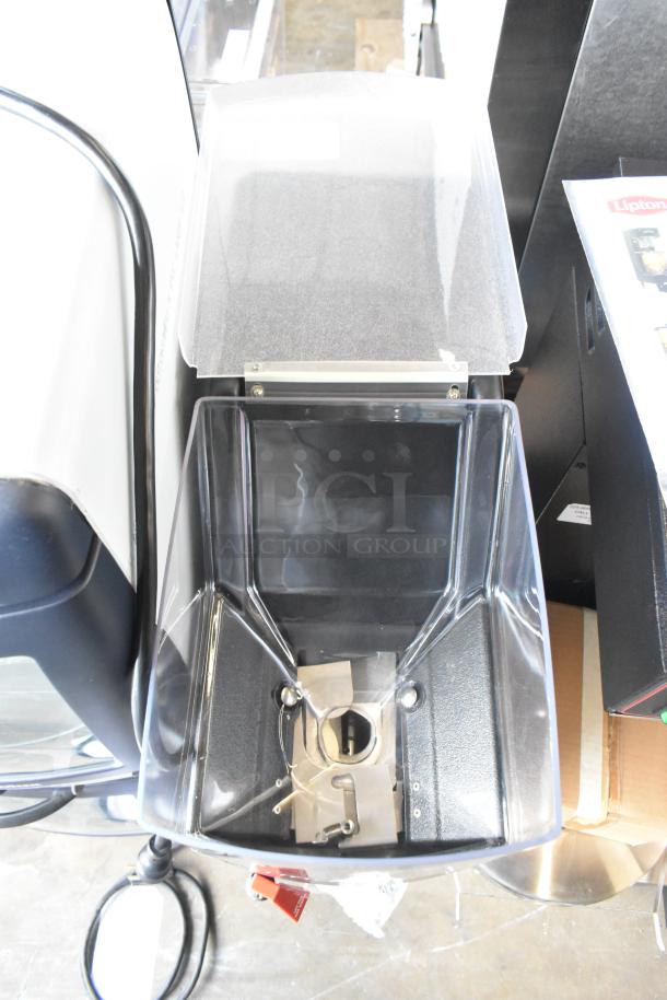 Grindmaster Grind N Brew coffee grinder and maker with stainless steel body, hot water dispenser, and metal brew basket.