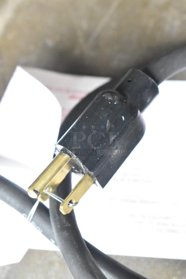 Black power plug with a cable, shown in close-up. No visible markings or identifiers.