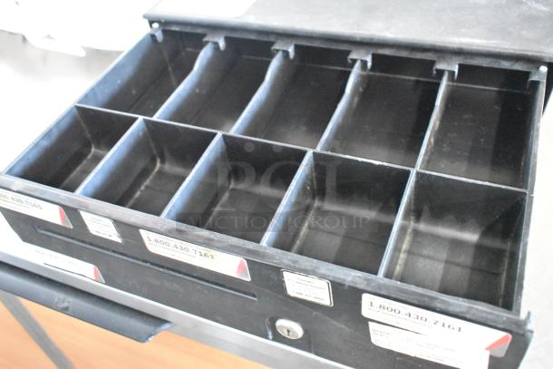 Metal cash drawer, black with multiple compartments, visible key lock, and contact labels on front. Good condition.