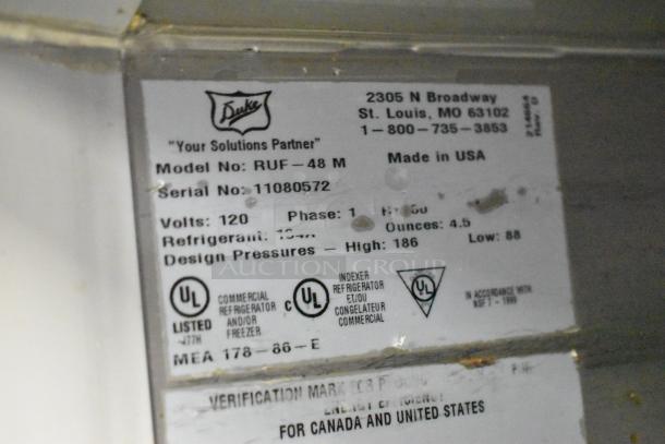 Duke RUF-48M stainless steel commercial cooler label showing model, serial number, voltage, and manufacturing details.