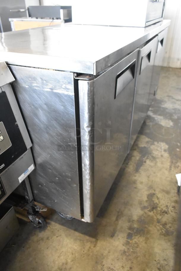 Migali C-U72R 3 Door Undercounter Cooler, stainless steel, commercial casters, 115V, 1 phase, visible wear on doors.