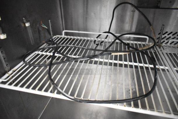 Migali C-U72R stainless steel 3-door undercounter cooler interior with wire shelving and electrical cords. Suitable for commercial use.