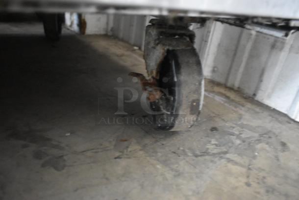 Rusty caster under the Migali C-U72R commercial cooler. Visible wear on the wheel, suitable for heavy-duty use.