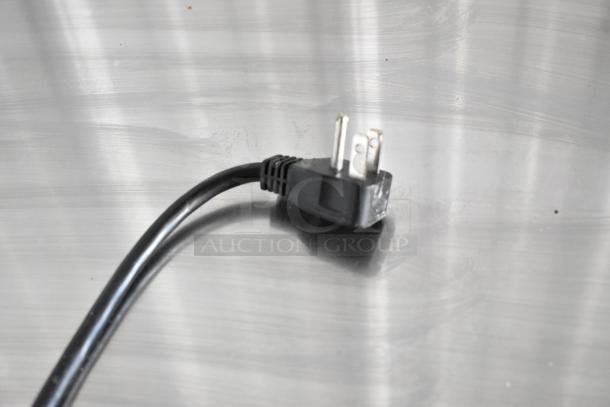 Power plug of Arctic Air AUB65RZ commercial bar cooler, shown on metal surface, indicating electrical compatibility.
