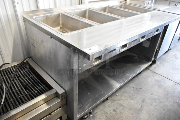 Standex TM-90D stainless steel 4 bay steam table with under shelf, in good condition, on commercial casters, 208V, 1 phase.
