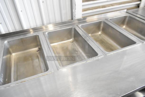 Standex TM-90D stainless steel 4-bay steam table, electric powered, with under shelf, commercial casters, 208 volts, 1 phase.