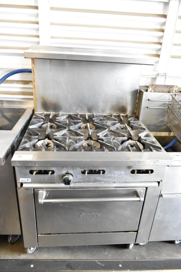 Garland SunFire stainless steel 6-burner gas range with oven, overshelf, backsplash, on commercial casters. Signs of use.