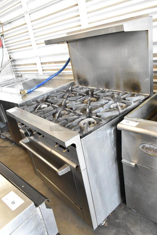 Garland SunFire stainless steel gas-powered 6 burner range with oven, over shelf, backsplash, and casters, used condition.